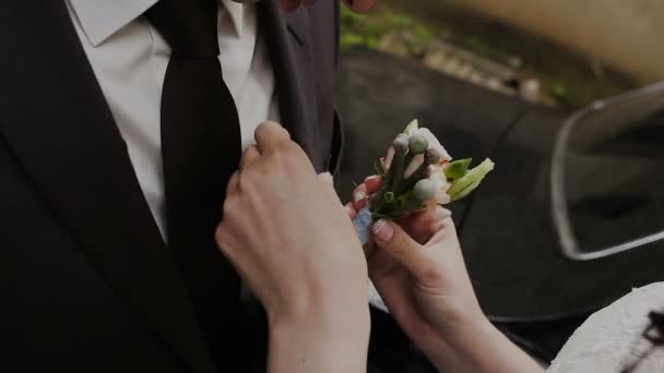 Bruid heeft haar bruidegoms pak op corsages oplegt. Wedding voorbereiding — Stockvideo