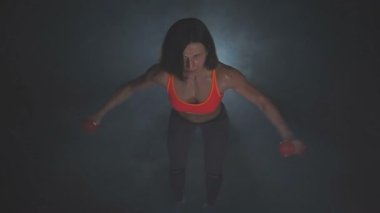 Dambılları kaldıran güzel bir fitness kadını. Sportif kız iyi eğitilmiş vücudunu gösteriyor. Güç eğitimiyle gelişmiş kaslar. .
