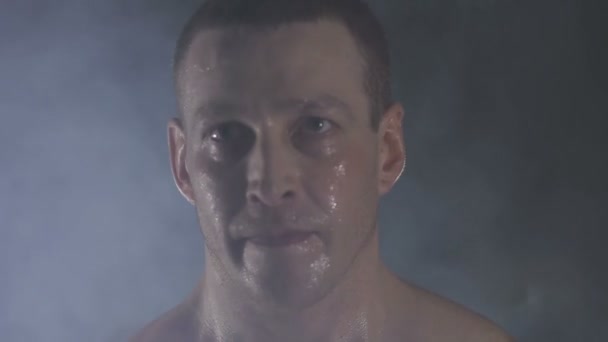 Сильный спортсмен поднимает тяжелые гантели в дыму — стоковое видео