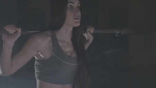 Imagen completa de una mujer joven probando su fuerza sosteniendo una barra con pesas pesadas sobre sus hombros mientras se agacha — Vídeos de Stock