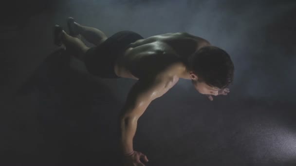 Young man pushes up from wooden floor in gym — Stock Video