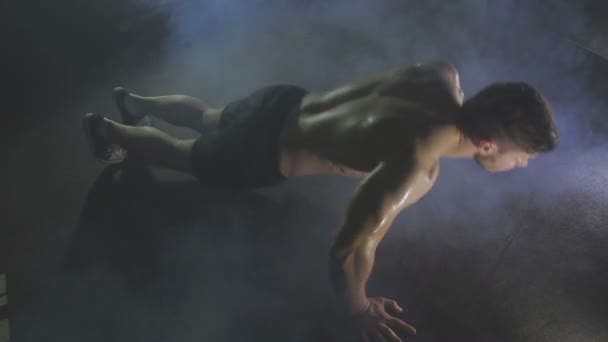 Joven empuja hacia arriba desde el suelo de madera en el gimnasio — Vídeo de stock