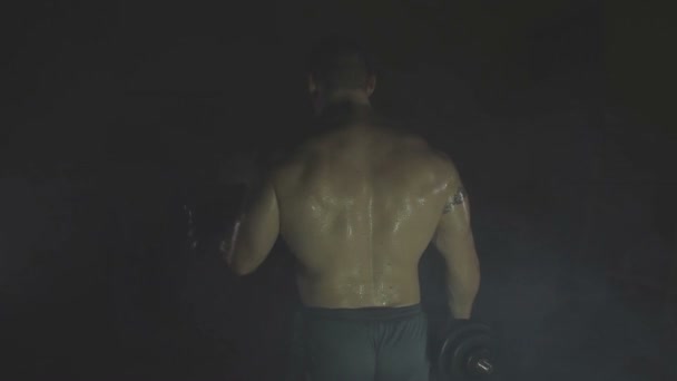 Fuerte deportista levantando pesadas mancuernas en humo — Vídeos de Stock