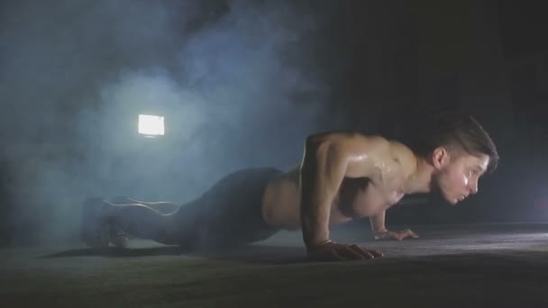 Joven empuja hacia arriba desde el suelo de madera en el gimnasio — Vídeo de stock