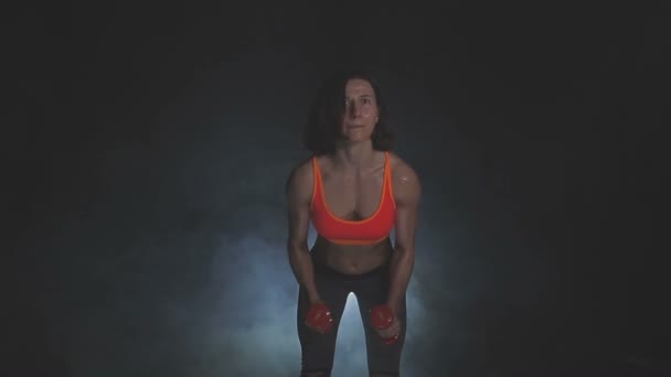 Mooie fitnessvrouw met heffende halters. Sportief meisje die haar goed getrainde lichaam laat zien. Goed ontwikkelde spieren door krachttraining . — Stockvideo