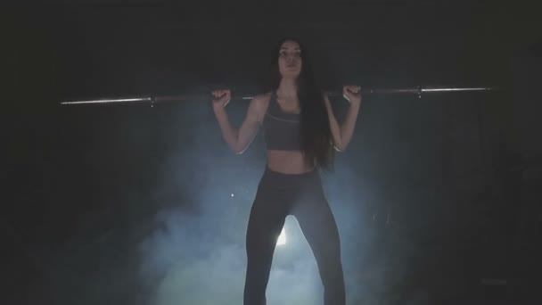 Εικόνα πλήρους μήκους του μια νεαρή γυναίκα δοκιμές τη δύναμή της, κρατώντας ένα barbell με μεγάλα βάρη στους ώμους της, όπως εκείνη καταλήψεις — Αρχείο Βίντεο
