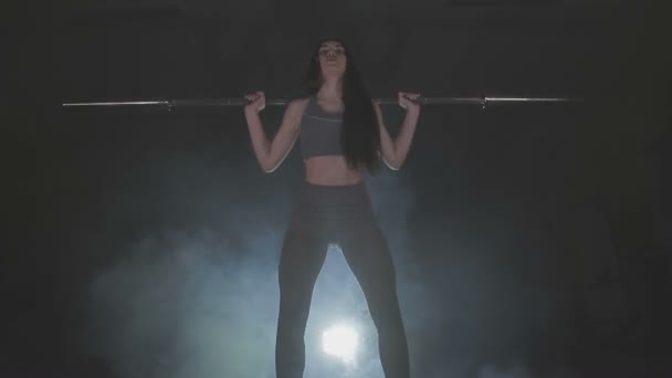 Immagine completa di una giovane donna che prova la sua forza tenendo un bilanciere con pesanti pesi sulle spalle mentre si accovaccia — Video Stock