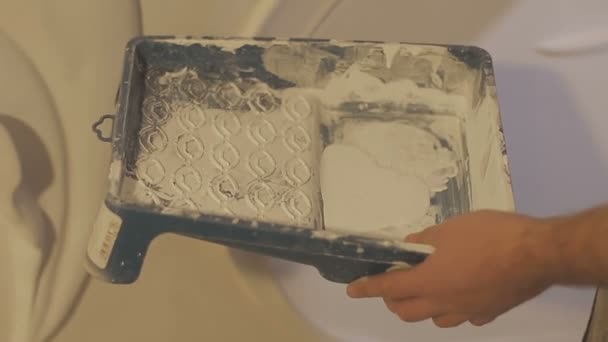 Knochenweiße Farbe wird aus Dose in Plastiktablett gegossen — Stockvideo