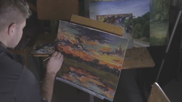 De kunstenaar schildert een schilderij in de studio — Stockvideo