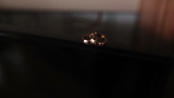 Mooie camera vlucht naar de trouwringen die op de hoek met een gelakte coating liggen — Stockvideo