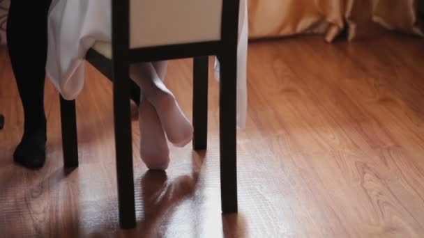 Pieds nus fille sur une chaise près de la fenêtre — Video