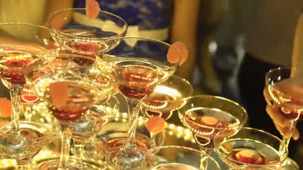 Een mooie piramide van glazen met champagne en stukjes fruit erin — Stockvideo