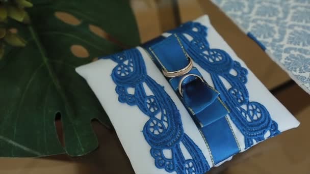 Wedding rings on a cushion with blue patterns. — Stock Video