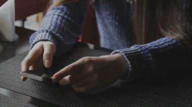 Kız bir kafe ve seyir telefon bir masada oturur