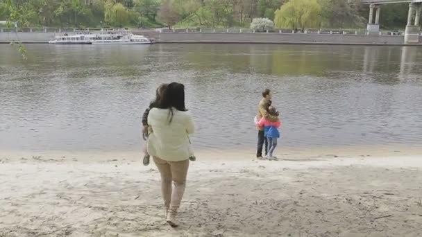 Rodina chodí na břehu řeky v teplém počasí — Stock video