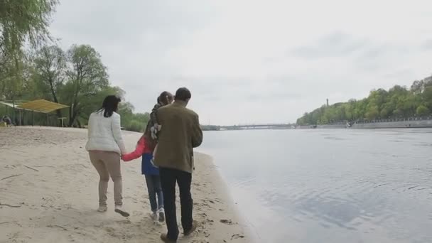 Rodina chodí na břehu řeky v teplém počasí — Stock video