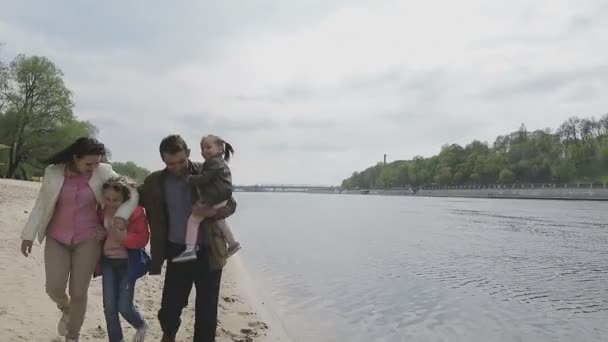 Rodina chodí na břehu řeky v teplém počasí — Stock video