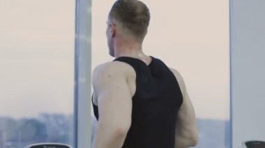 Bir adam bir fitness kulübünde bir koşu bandı üzerinde pratik.