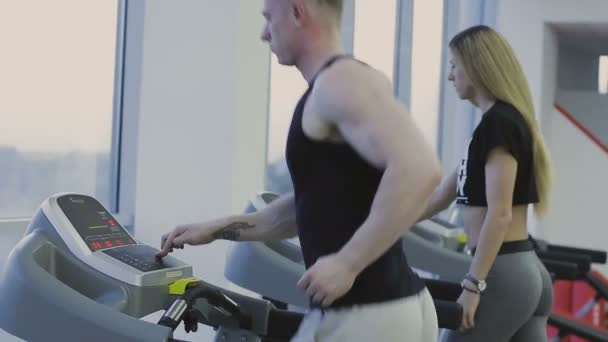 Muž a dívka jsou školení na běžícím pásu ve fitcentrum — Stock video