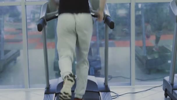 Un hombre está practicando en una cinta de correr en un gimnasio . — Vídeos de Stock