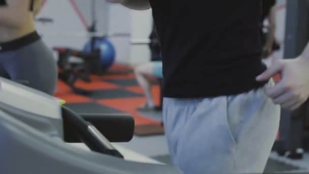 Um homem está praticando em uma esteira em um clube de fitness . — Vídeo de Stock