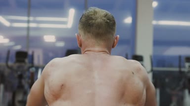 Bir fitness kulübünde fitness makinede kaslı bir adam çıplak bir gövde ile trenler