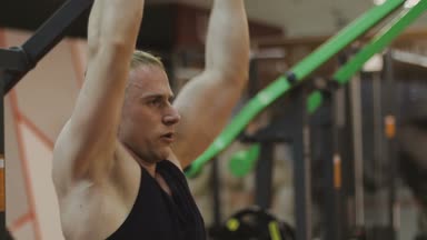 Siyah T-shirt kaslı bir adam bir fitness kulübünde fitness makinede eğitiyor.
