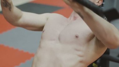 Bir fitness kulübünde fitness makinede kaslı bir adam çıplak bir gövde ile trenler