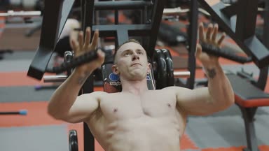 Bir fitness kulübünde fitness makinede kaslı bir adam çıplak bir gövde ile trenler