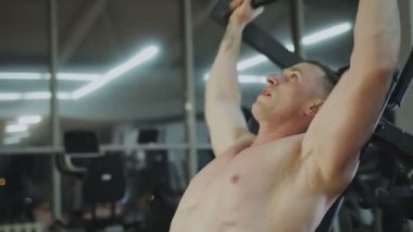 Bir fitness kulübünde fitness makinede kaslı bir adam çıplak bir gövde ile trenler