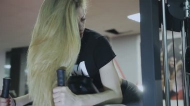 Çok güzel kadın eğitmen trenler bir fitness kulübünde fitness makinedeki