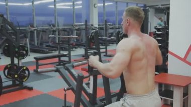 Bir fitness kulübünde fitness makinede kaslı bir adam çıplak bir gövde ile trenler