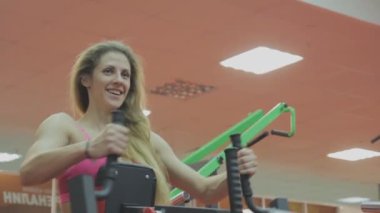 Çok güzel kadın eğitmen trenler bir fitness kulübünde fitness makinedeki