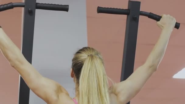Тренер фитнес-клуба делает подтягивания на тренажере для укрепления мышц плеч. Женщина делает упражнения правильно, тянет вверх с прямой спиной — стоковое видео