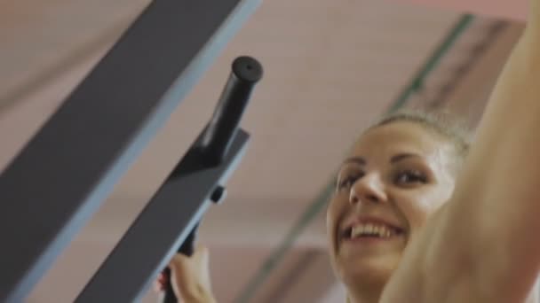 Fitness trenér sportovního klubu dělá shybů na simulátoru pro posílení ramenních svalů. Žena dělá cvičení správně, tahání s rovnými zády — Stock video