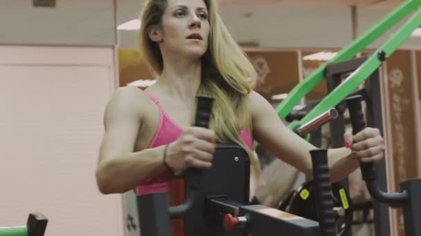 Πολύ όμορφη γυναίκα προπονητής τρένα σε ένα μηχάνημα γυμναστικής στο γυμναστήριο — Αρχείο Βίντεο