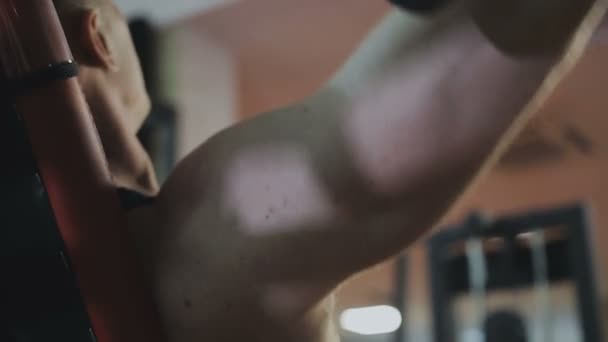 Siyah T-shirt kaslı bir adam bir fitness kulübünde fitness makinede eğitiyor. — Stok video