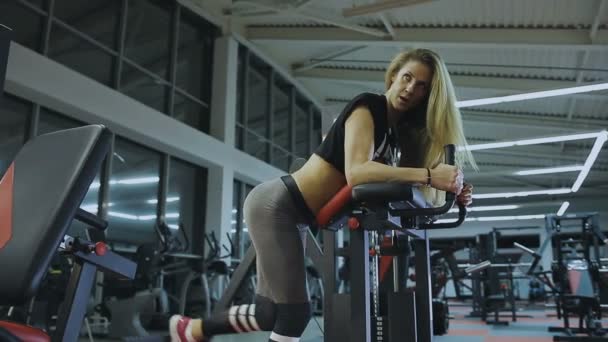 Treinador feminino muito bonito treina em uma máquina de fitness em um clube de fitness — Vídeo de Stock
