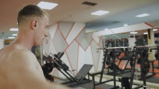 Um homem está a treinar com halteres no ginásio. — Vídeo de Stock