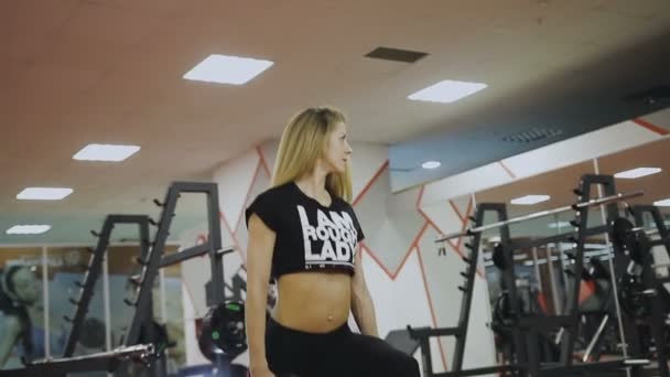 Mujer está entrenando con pesas en el gimnasio — Vídeos de Stock