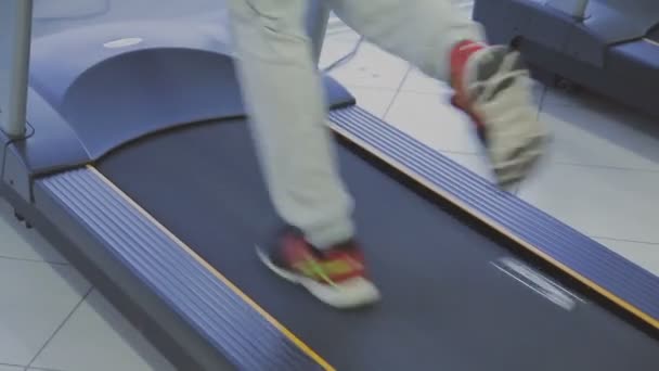 Um homem está praticando em uma esteira em um clube de fitness . — Vídeo de Stock