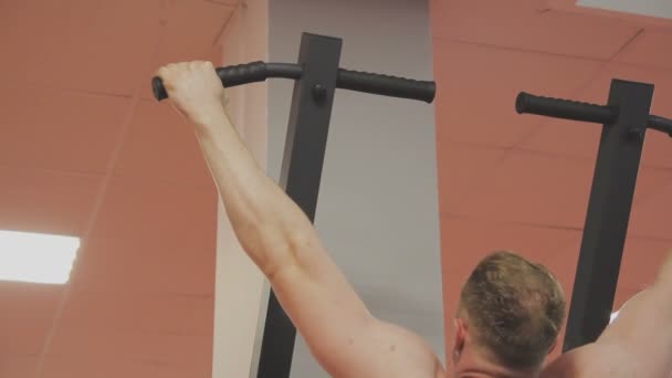 De man trekt op de balk in de fitnessclub — Stockvideo