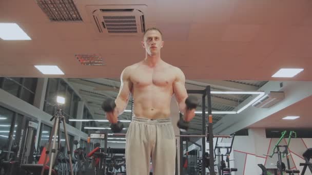 Ein Mann trainiert mit Hanteln im Fitnessstudio — Stockvideo