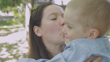 Aile ile çocuk parkta yürüyor. Güneşli bir gün. Yeşil ağaçlar