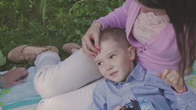 Aile ile çocuk parkta yürüyor. Güneşli bir gün. Yeşil ağaçlar