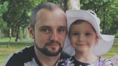 Aile ile çocuk parkta yürüyor. Güneşli bir gün. Yeşil ağaçlar