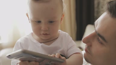 Küçük bir çocuk bir smartphone ile oynuyor. Aile evde