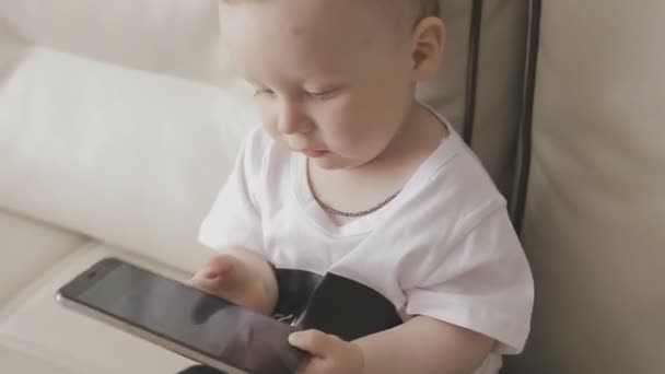 Маленький ребенок играет со смартфоном. Семья на дому — стоковое видео