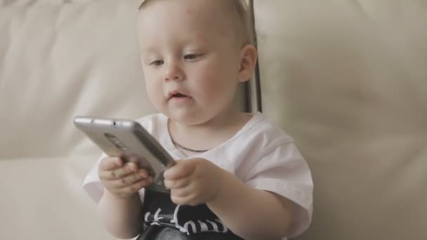 Un petit enfant joue avec un smartphone. Famille à la maison — Video