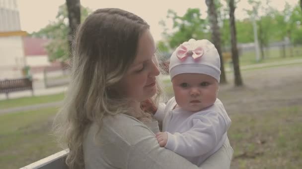 Όμορφη γυναίκα με τα πόδια με τη μικρή της κόρη και σπρώχνοντας το καρότσι στο πάρκο — Αρχείο Βίντεο